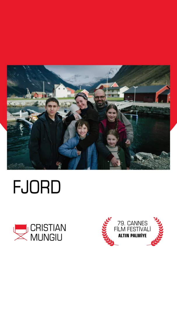Fjord filminin bir sahnesinde, arkasında karlı dağlar ve iskelede bağlı teknelerle dolu sakin bir fiyort köyü manzarası önünde, bir bebek tutan kadın ve bir erkek ile dört çocuğun gülümseyerek kameraya baktığı samimi bir aile pozu yer alıyor.