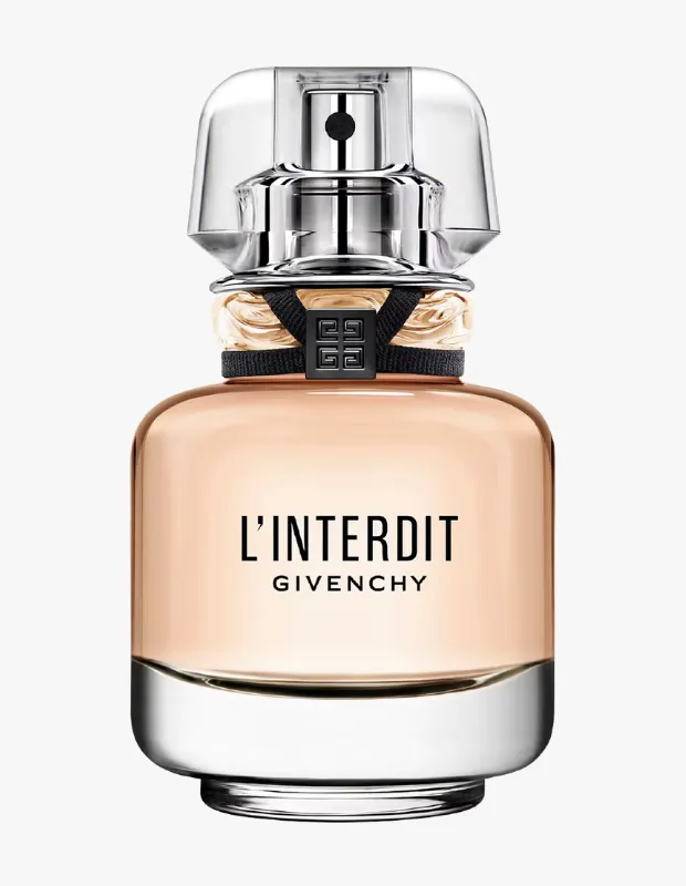 Beyaz bir arka plan üzerinde duran, içinde şeftali rengi sıvı bulunan Givenchy L'Interdit parfüm şişesi; şeffaf kapağı, gümüş renkli püskürtücü mekanizması ve boynunda Givenchy logosu taşıyan zarif siyah kurdele detayıyla öne çıkıyor.