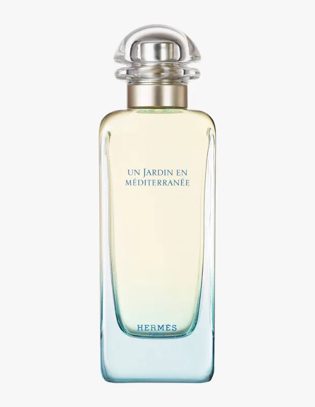 Bu görselde, Hermès'in Akdeniz'in yeşil bahçelerinden ilham alan benzersiz kokusu Un Jardin en Méditerranée'nin, zarif ve şeffaf şişesi, içindeki hafif yeşilimsi sıvısıyla birlikte doğal ışık altında, markanın doğa temalı koleksiyonunun ruhunu yansıtan bir atmosferde sergileniyor.