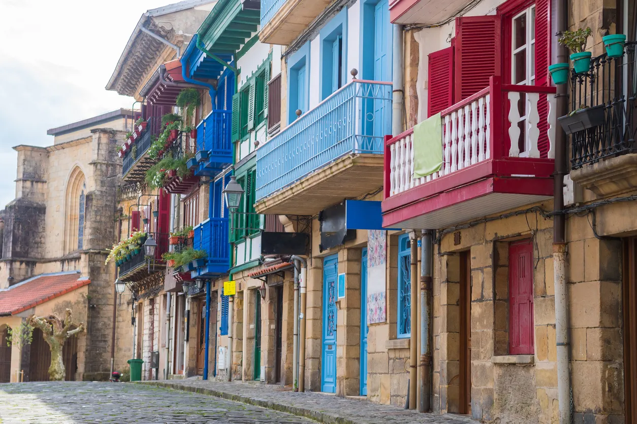 Hondarribia'nın dar sokaklarından birinde sıralanmış, geleneksel Bask mimarisinin karakteristik özelliklerini yansıtan, canlı renklerdeki evlerin oluşturduğu büyüleyici bir görüntü, bu sahil kasabasının kendine özgü atmosferini ve kültürel dokusunu gözler önüne seriyor.