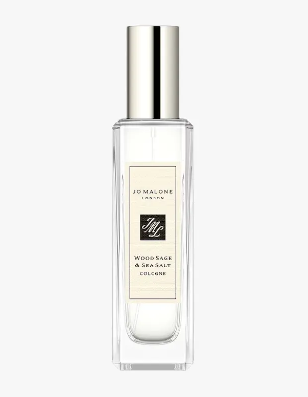 Jo Malone London markasının imzası niteliğindeki şeffaf cam şişesinde, gümüş kapaklı ve WOOD SAGE & SEA SALT COLOGNE etiketli bu özel kolonya, sade ve aydınlık bir ortamda dikkat çekici bir şekilde konumlandırılmış, ürünün doğal ve ferahlatıcı özünü yansıtıyor.