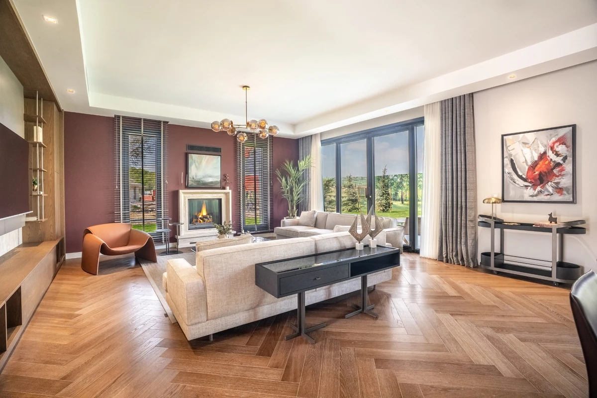 Büyük cam kapılardan yemyeşil doğa manzarasının içeri süzüldüğü, balıksırtı parke zeminli, modern ve geniş bir salon; yanan şöminenin sıcaklığı ve krem rengi rahat koltuklarıyla Kasaba Modern projesindeki gibi şehirde doğayla iç içe, huzurlu bir slow living deneyimi sunan sakin bir yaşam köşesi.