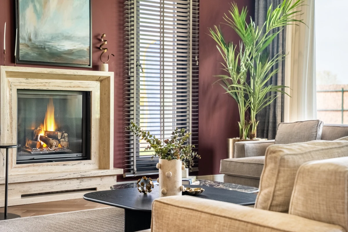 Modern bir salonun odak noktası olan, minimalist ahşap ve taş detaylarıyla zenginleştirilmiş şık bir şöminenin yakın çekim görüntüsü; çağdaş tasarımıyla mekanın sıcak ve davetkar atmosferine vurgu yapmaktadır.