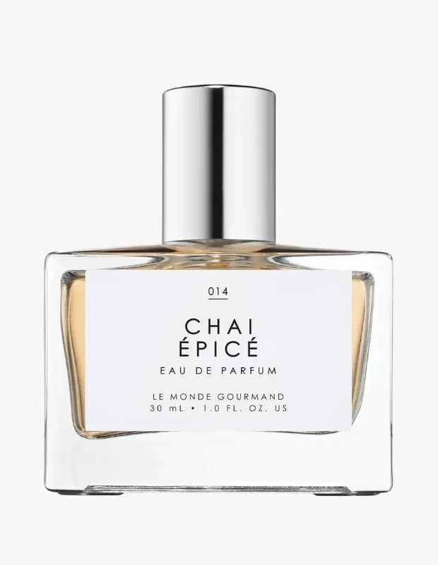 Beyaz etiketinde 014 Chai Épicé Eau de Parfum Le Monde Gourmand 30 mL yazan, şık gümüş renkli silindirik kapaklı, dikdörtgen şeffaf cam şişedeki amber renkli Le Monde Gourmand Chai Épicé parfümü, ürünün genel görünümünü vurguluyor.