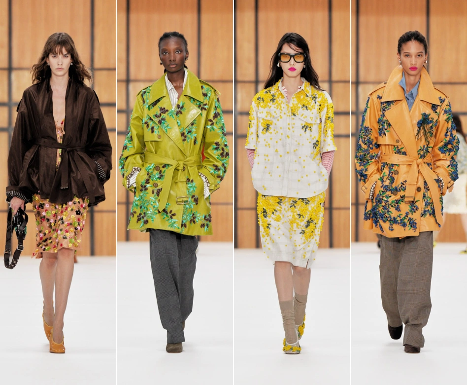 Dört model, Burberry'nin Londra Moda Haftası podyumunda, biri kahverengi ceket ve çiçekli elbise, diğeri detaylı yeşil çiçek nakışlı trençkot, üçüncüsü sarı çiçek desenli beyaz takım ve sonuncusu mavi çiçek nakışlı turuncu trençkot giyerek yeni koleksiyonlarını sergiliyor.