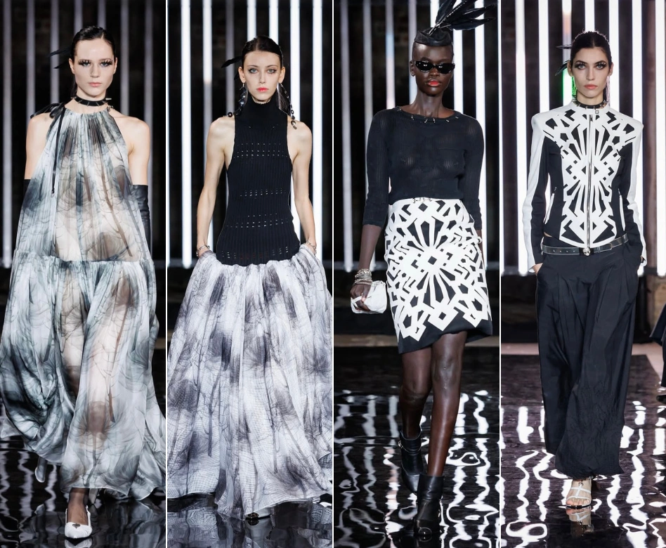 Londra Moda Haftası kapsamında John Richmond'ın dinamik koleksiyonundan bir parça sergileyen: Parlak siyah, metalik dokulu detaylarla zenginleştirilmiş, omuzları belirgin ve keskin hatlara sahip bir ceket ile uyumlu midi etek giyen, podyumda kendine güvenle yürüyen bir kadın model.