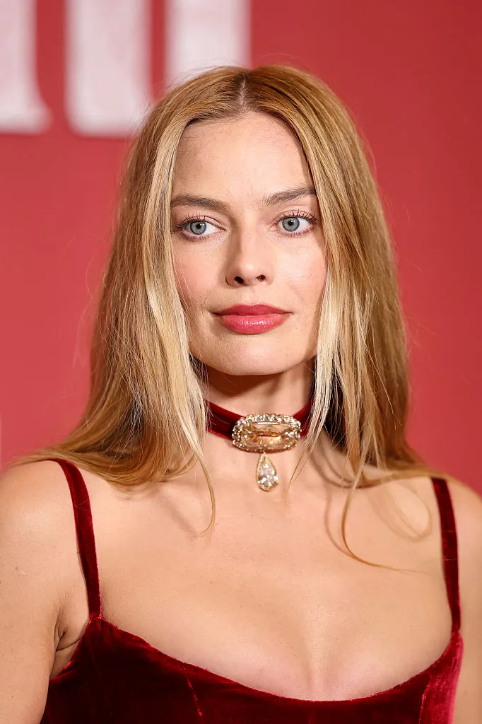 Parlak sarı saçları, hafif dalgalı modeli ve sıcak gülümsemesiyle doğrudan kameraya bakarak poz veren Margot Robbie, her zaman olduğu gibi kendi özel stilini yansıtan zarif bir kıyafetle bu karede de moda dünyasındaki etkileyici yerini vurguluyor.