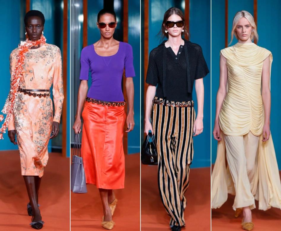 New York Moda Haftası'nda Tory Burch defilesinden dört model, podyumda göz alıcı kıyafetleriyle yürüyor; solda şeftali rengi işlemeli ve omuzdan fırfırlı uzun elbisesiyle bir model, yanında mor bluz ve parlak turuncu etekle güneş gözlüklü başka bir model, ortada siyah polo yaka üst ve siyah-bej çizgili geniş paça pantolon giyen bir model ve sağda krem rengi büzgülü üst ve arkadan uzun drapeli etek detayı olan bir kıyafetle son model yer alıyor.