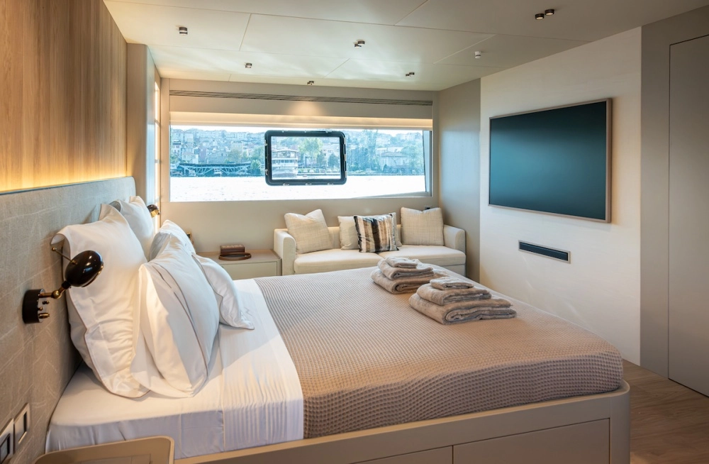 Numarine 27XP yatının şık sahibi kabini, beyaz nevresimler ve bej waffle desenli örtüyle hazırlanmış geniş bir yatağın yanı sıra, suya ve karşıdaki binalara bakan geniş panoramik bir pencereye, rahat bir dinlenme kanepesine ve duvara monte edilmiş modern bir televizyona sahiptir.