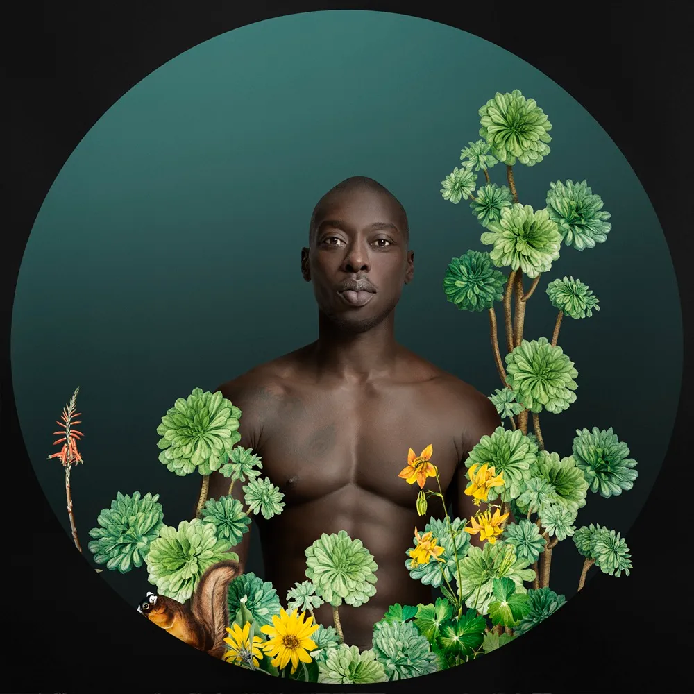 Sanatçı Omar Victor Diop'un imzası niteliğindeki bu portre fotoğrafında, canlı desenli ve çok renkli giysiler giyen, koyu çerçeveli büyük gözlüklü bir figür, kimlik ve kültürel miras temalarını yansıtan düşünceli bir ifadeyle kadrajda yer alıyor.