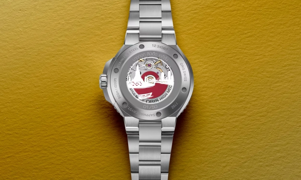 Oris Aquis Bangkok Limited Edition dalış saatinin şeffaf arka kapağından tüm ihtişamıyla gözler önüne serilen, karmaşık dişli sistemi ve kusursuz işlemeli rotor detaylarıyla bezenmiş otomatik mekanizma, markanın üstün saatçilik ustalığını vurguluyor.