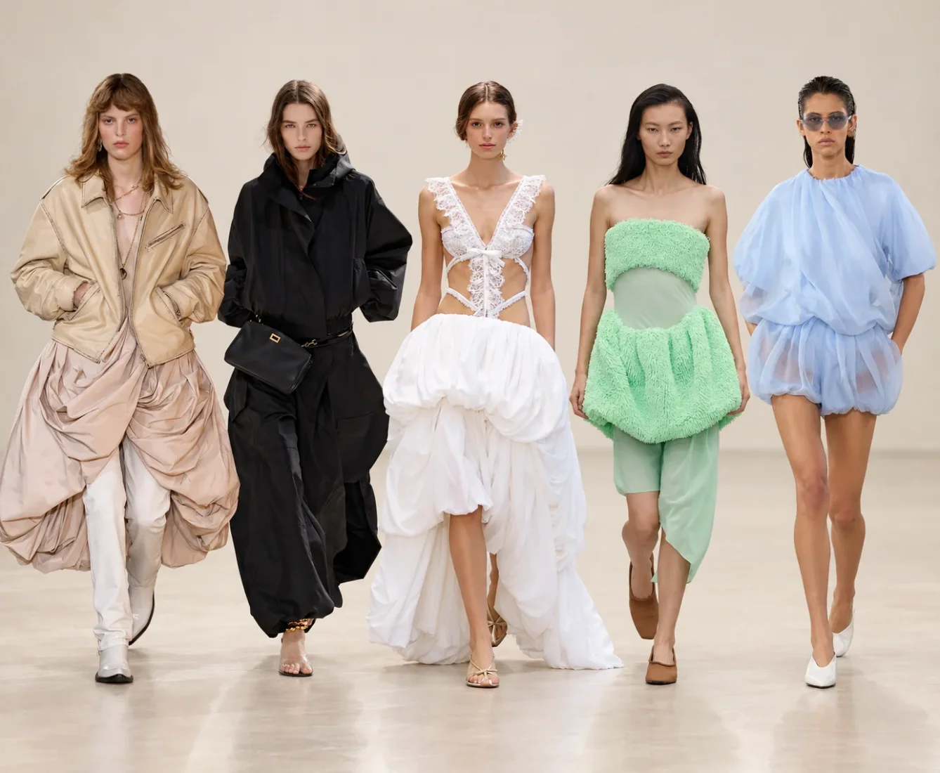 Paris Moda Haftası'nın öne çıkan trendlerinden balon hacimleri mükemmel bir şekilde yansıtan, abartılı puf kolları ve dökümlü eteğiyle modern ve cesur bir duruş sergileyen, sezonun dikkat çekici moda akımını vurgulayan bir giysi içinde model.