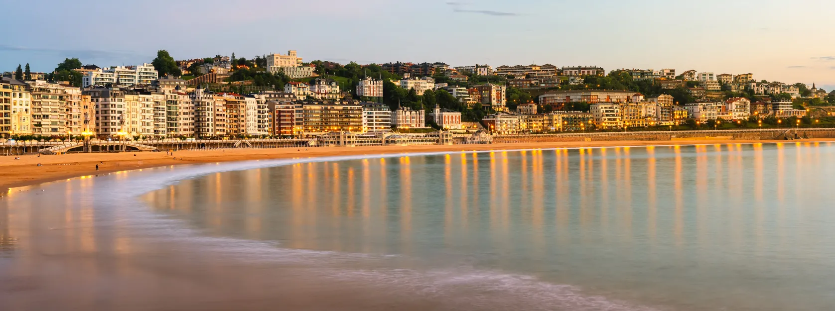 San Sebastián'ın meşhur La Concha plajında, yemyeşil tepelerle çevrili şehrin eşsiz mimarisinin denize karıştığı noktada, pırıl pırıl güneşli bir günde denizin ve altın rengi kumun tadını çıkaran sayısız insanın oluşturduğu hareketli ve davetkar bir atmosfer.