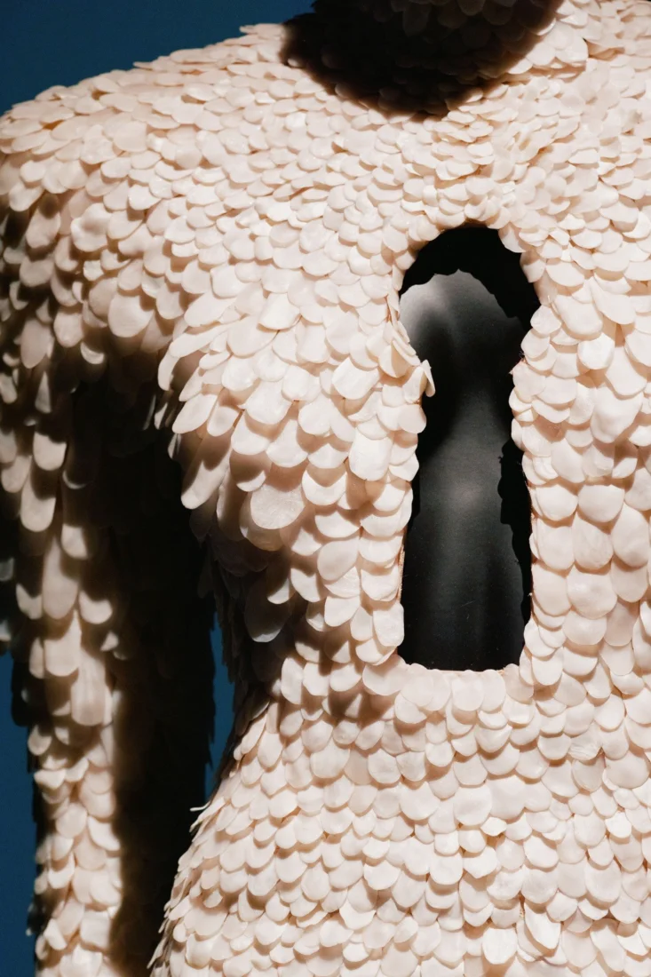Elsa Schiaparelli'nin haute couture koleksiyonlarından birine ait, belirgin omuz hatları ve mimari formuyla dikkat çeken, sanatsal bir detayla süslenmiş, kadının üzerinde kusursuzca duran bu tasarım, moda dünyasındaki yenilikçi ve sürrealist ruhu başarıyla yansıtıyor.