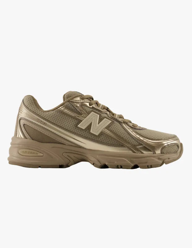 New Balance markalı, file detaylı ve metalik parlak panellere sahip, bronz tonlarındaki kalın tabanlı modern spor ayakkabı, seyahat stil rehberi için konforlu ve şık bir seçenek sunarak beyaz bir arka plan üzerinde özenle sergileniyor.
