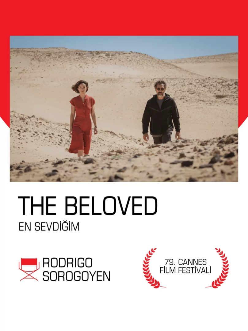 En Sevdiğim filminin çöl temasını vurgulayan bu çarpıcı görselde, kırmızı bir tulum giyen bir kadın ile koyu renk ceketli bir adam, zorlu kumlu ve kayalık bir arazide yavaşça ilerleyerek, Filmekimi'nin derin ve sürükleyici hikayeler sunma geleneğini yansıtan bir yolculuğun başlangıcını tasvir ediyor.