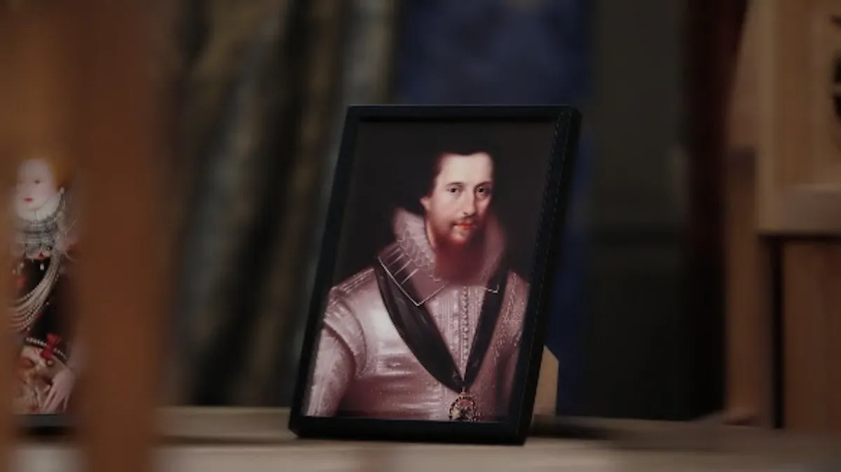Tudorlar dönemine ait, siyah çerçeveli ve hafif eğik duran bir portrede, rüf yakalı, beyaz işlemeli giysiler içinde, göğsünde madalya bulunan, hafif sakallı ve ciddi bakışlı genç bir adam resmedilmiş; sol tarafta ise kraliçe figürlü bir heykelciğin bulanık görüntüsü tarihi atmosferi tamamlıyor.
