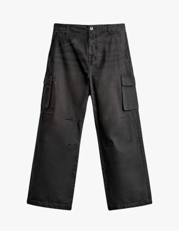 Koyu gri renkteki bu Zara cargo pantolon, yanlardaki büyük kargo cepleri, rahat ve geniş paça kesimi ile öne çıkıyor, üst kısmında ve ceplerinde görülen hafif eskitilmiş, yer yer soluk ve noktacıklı yüzey detaylarıyla modern bir görünüm sunuyor.