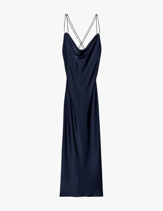 Canlı ve akışkan koyu lacivert saten kumaştan tasarlanmış, önü şık bir drape yaka detayına sahip, arkası çapraz ince askılı ve boydan inen zarif bir slip elbise, modern duruşuyla dikkat çekiyor.