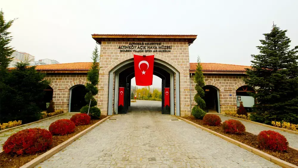 Altınköy Açık Hava Müzesi'nin geniş bir bölümünü gösteren bu manzara fotoğrafında, toprak bir yolun kenarında sıralanmış geleneksel ahşap evler ve çiftlik binaları, yemyeşil doğayla çevrili bulutlu bir gökyüzünün altında tarihi bir köy atmosferi sunuyor.