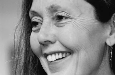 Modern edebiyatın önde gelen şairlerinden Anne Carson, kısa saçları, belirgin gözlükleri ve derin düşünceli bakışıyla objektife odaklanmış bir şekilde portresinde beliriyor; bu ifade onun entelektüel derinliğini ve sanatsal duruşunu vurguluyor.