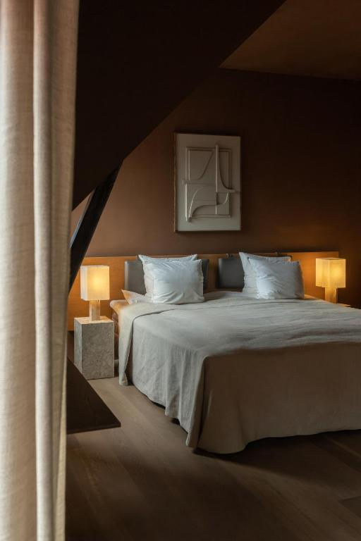 Audo House'un modern ve minimalist tasarım anlayışını yansıtan, doğal ışıkla aydınlanmış geniş bir oturma alanında, açık renkli konforlu modüler bir kanepe önünde yuvarlak siyah bir sehpa, üzerinde dekoratif obje ve kitap ile şık, entegre raflar dikkat çekiyor.
