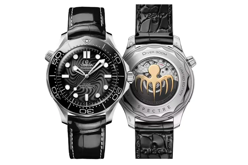Koyu renk ahşap özel üretim kutusunda, kadife astarlı iç kısımda zarifçe sergilenen, siyah kadranlı gümüş kasa Omega Seamaster dalış saati, yanında siyah-gri çizgili ek bir NATO kayış ve kayış değiştirme aletiyle birlikte, James Bond: Spectre filmi koleksiyoncuları için dikkat çekici bir parça olarak öne çıkıyor.