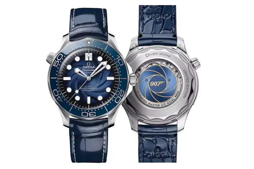 Açık koyu renk bir kutunun içinde, lacivert kadife bir yastık üzerinde duran, siyah kadranlı ve metalik bezelli gümüş renkli Omega Seamaster saat, siyah-gri çizgili NATO kayışıyla birlikte, James Bond Spectre filmiyle özdeşleşen ikonik tasarımını sergiliyor.