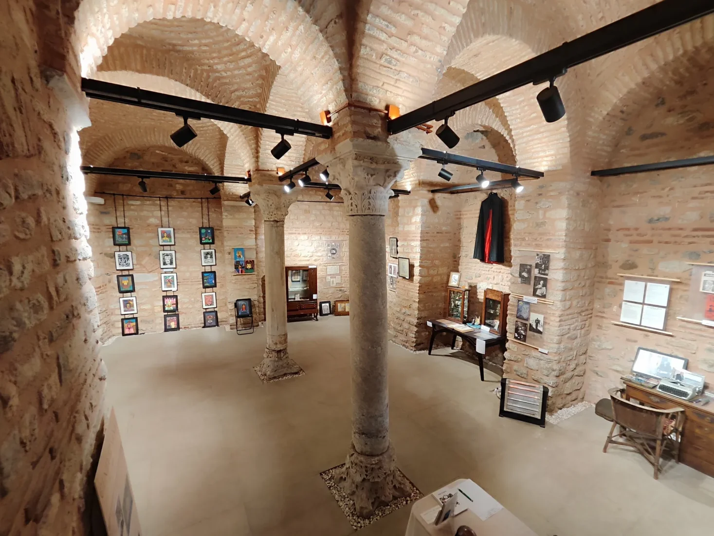 Ceneviz Sanat Evi'nin tarihi ve sanatsal kimliğini vurgulayan bu detaylı görselde, eski bir binanın özenle restore edilmiş taş cephesi ve kemerli pencereleri, geçmişin ruhunu günümüz sanatıyla birleştirerek ziyaretçileri ağırlamaya hazır.