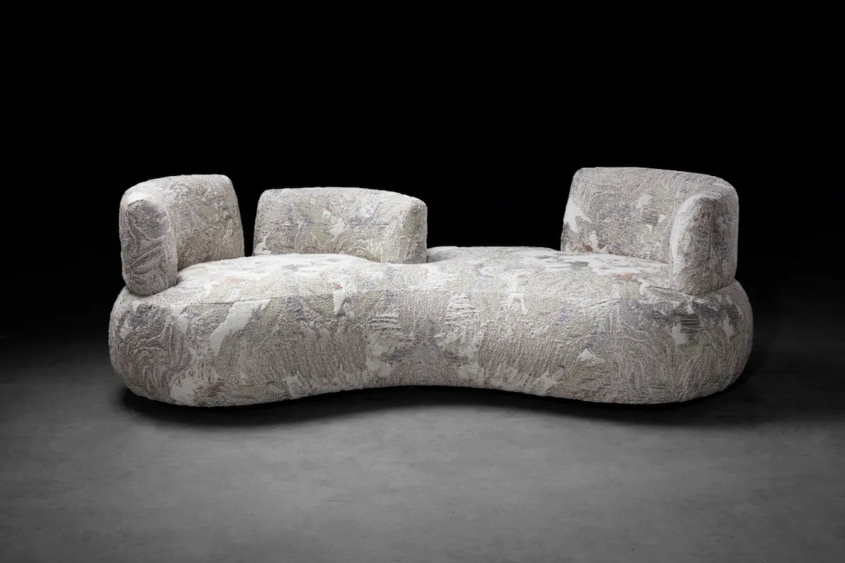 Studio KRJST'nin 2026 tarihli Sofa tasarımı; gri ve açık renkli, kıvrımlı, dokulu döşemeli kanepe.