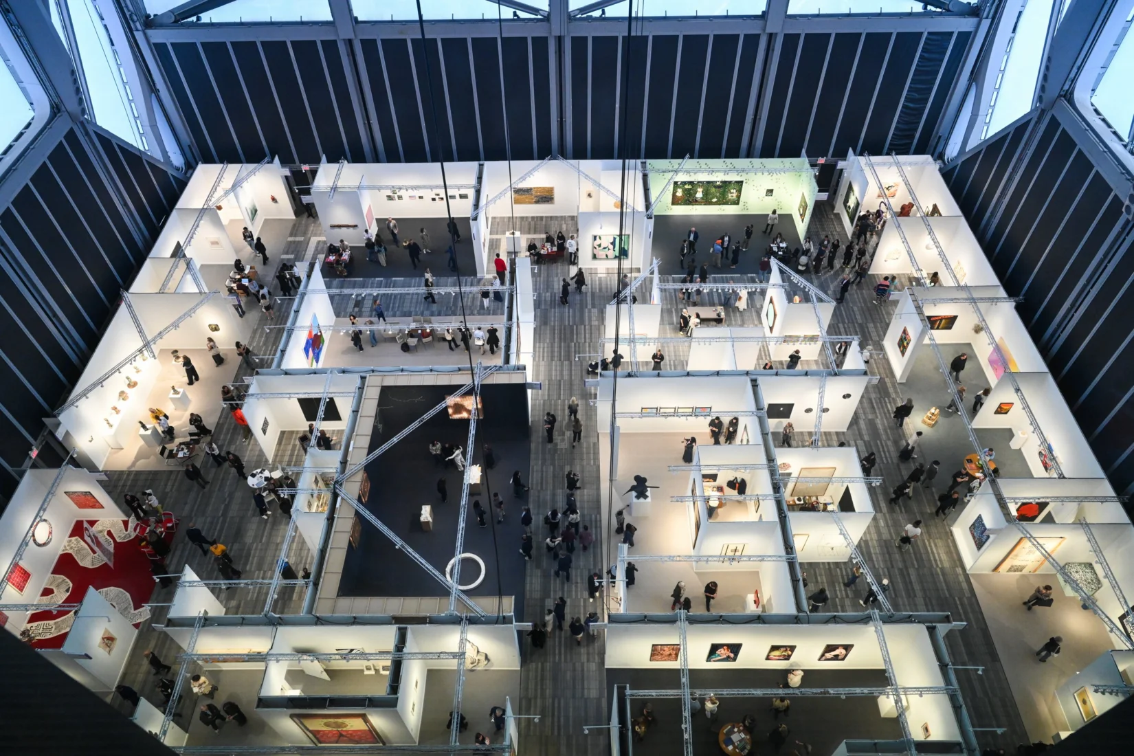 Frieze New York 2026 sanat fuarının hareketli atmosferinden, beyaz duvarlara asılı çeşitli modern sanat eserlerini ilgiyle inceleyen ziyaretçilerle dolu, geniş ve bol ışık alan bir sergi salonu genel görünümü.