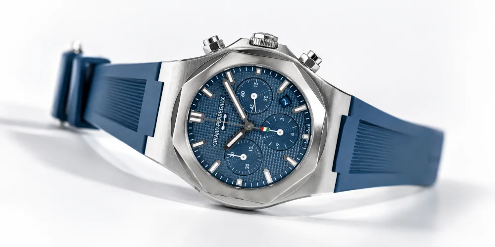 Girard-Perregaux Laureato Kronograf 42mm Azzurro kol saati, ışık yansımalarıyla dikkat çeken parlak metal kasa ve entegre bileziğiyle birlikte, mavi Guilloché desenli kadranında üç kronograf alt kadranı ve tarih penceresini belirgin bir şekilde sergiliyor.