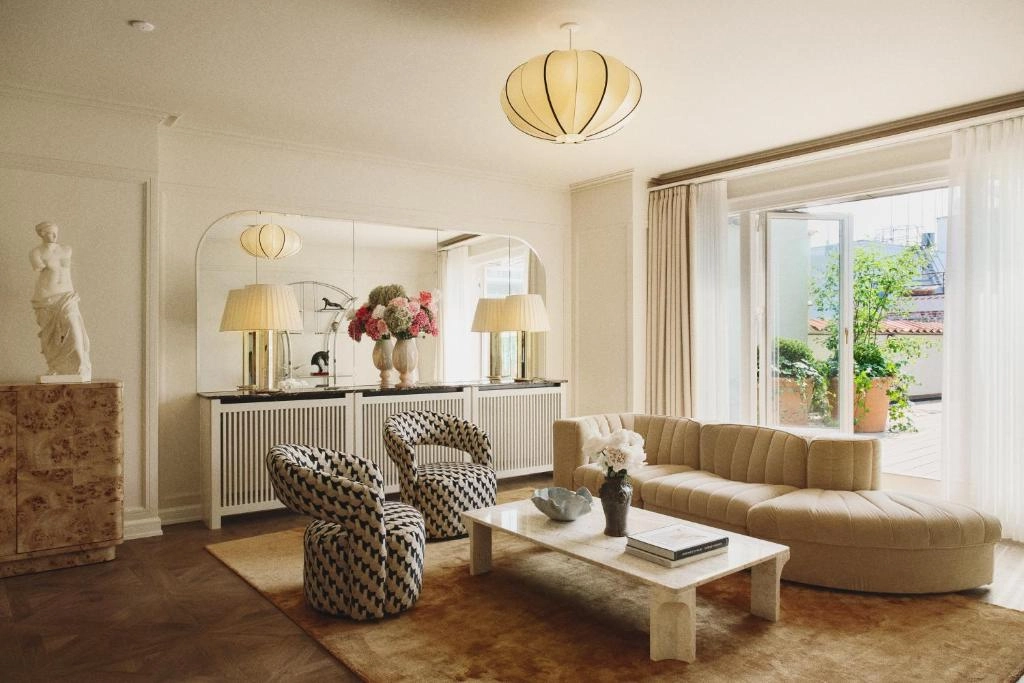Hotel Bella Grande'nin modern tasarımı ve konforu vurgulayan, beyaz çarşaflı, bol yastıklı büyük bir yatak, zarif bir komodin ve geniş penceresiyle lüks bir süit odası misafirlerini ağırlamaya hazır.