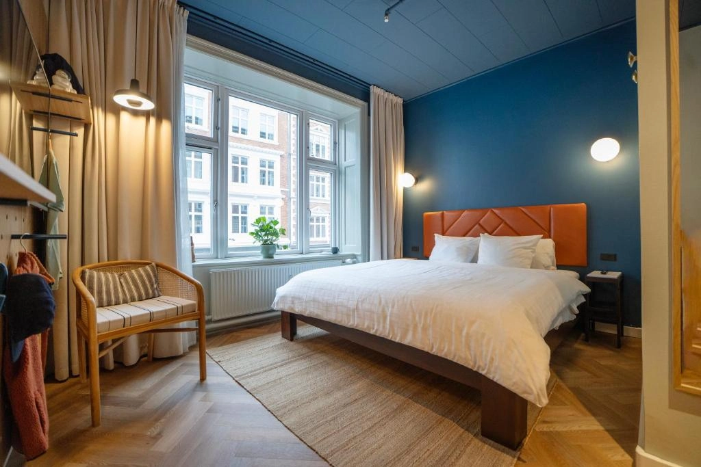 Hotel Mayfair'de, bej ve krem tonlarının hakim olduğu, modern çizgilerle harmanlanmış zarif bir tasarıma sahip, geniş çift kişilik yatağın, şık bir komodin ve sanatsal bir aydınlatmanın, yumuşak dokulu tekstillerin ve konforlu yatak takımının öne çıktığı, huzurlu bir konaklama deneyimi sunan lüks otel odası.