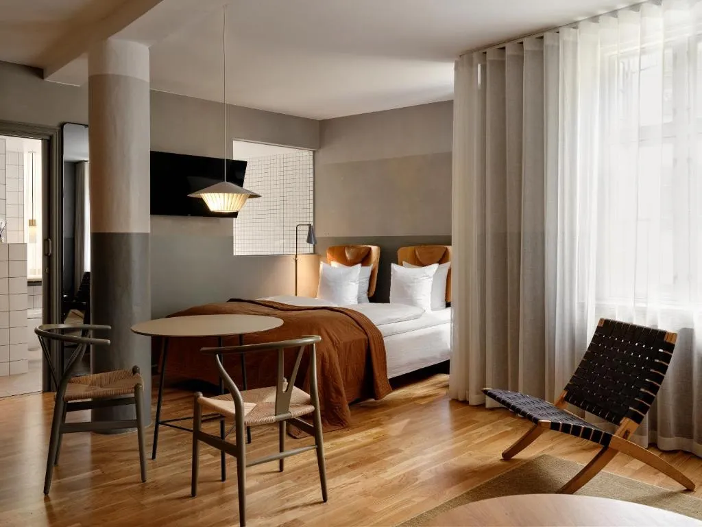 Hotel SP34'ün modern iç mimari tasarımını ve konforlu atmosferini vurgulayan, özenle seçilmiş mobilyalar ve sıcak aydınlatmalarla donatılmış, misafirlerin keyifli vakit geçirebileceği şık bir dinlenme veya karşılama alanı sahnesi.