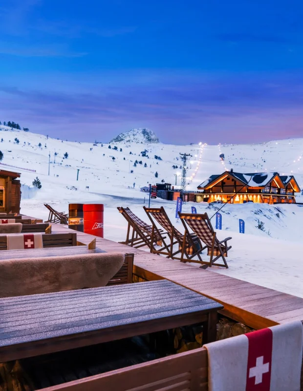 Akdeniz mimarisinden ilham alan Kaya Palazzo otelinin zarif ve modern çizgilerini sergileyen, etrafı yemyeşil peyzaj ve parlak havuzlarla çevrili, lüks bir tatil atmosferi sunan dış cephe görüntüsü.