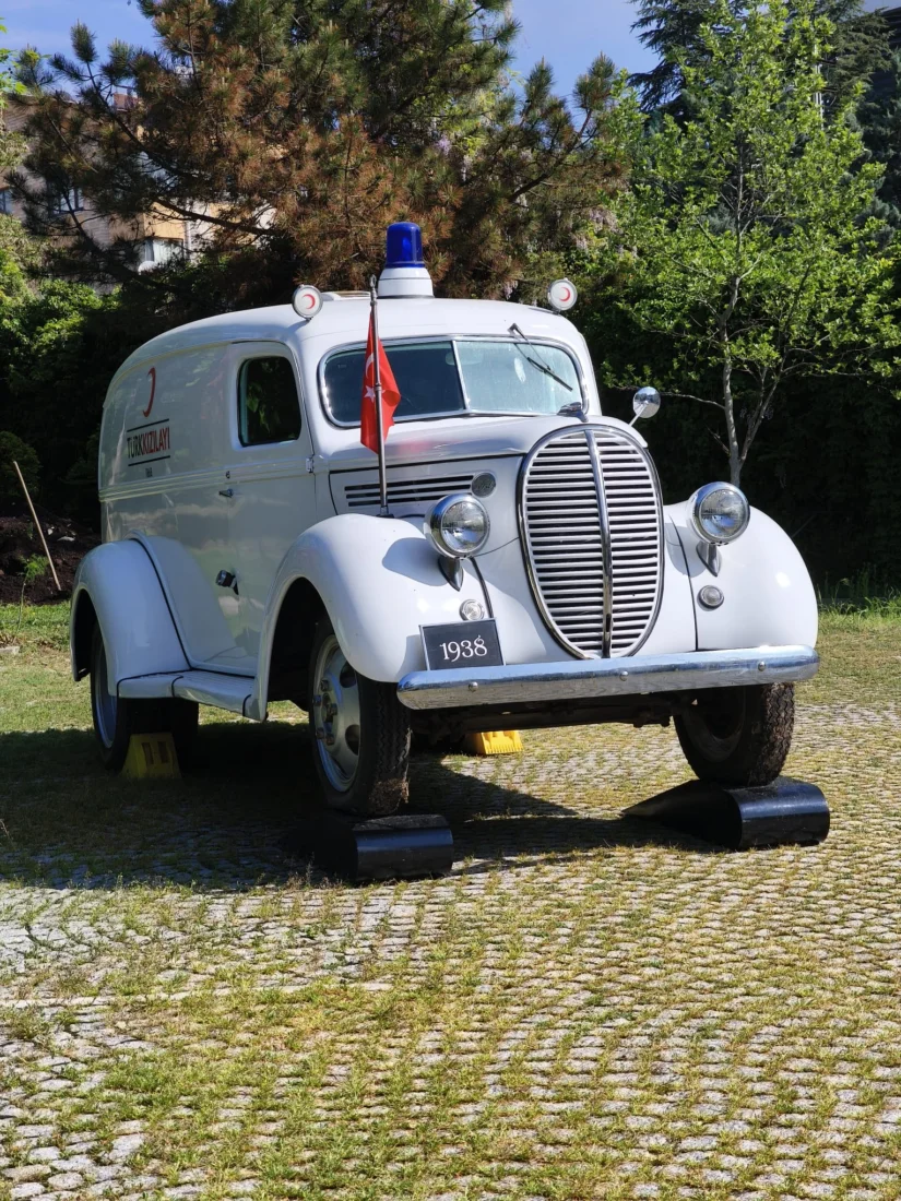 Koç sergisinin dikkat çeken eserlerinden biri olan, üzerinde büyük bir kırmızı haç bulunan parlak kırmızı ve beyaz renklerdeki bu vintage ambulans, tarihteki sağlık hizmetlerinin görsel bir temsilini sunuyor.