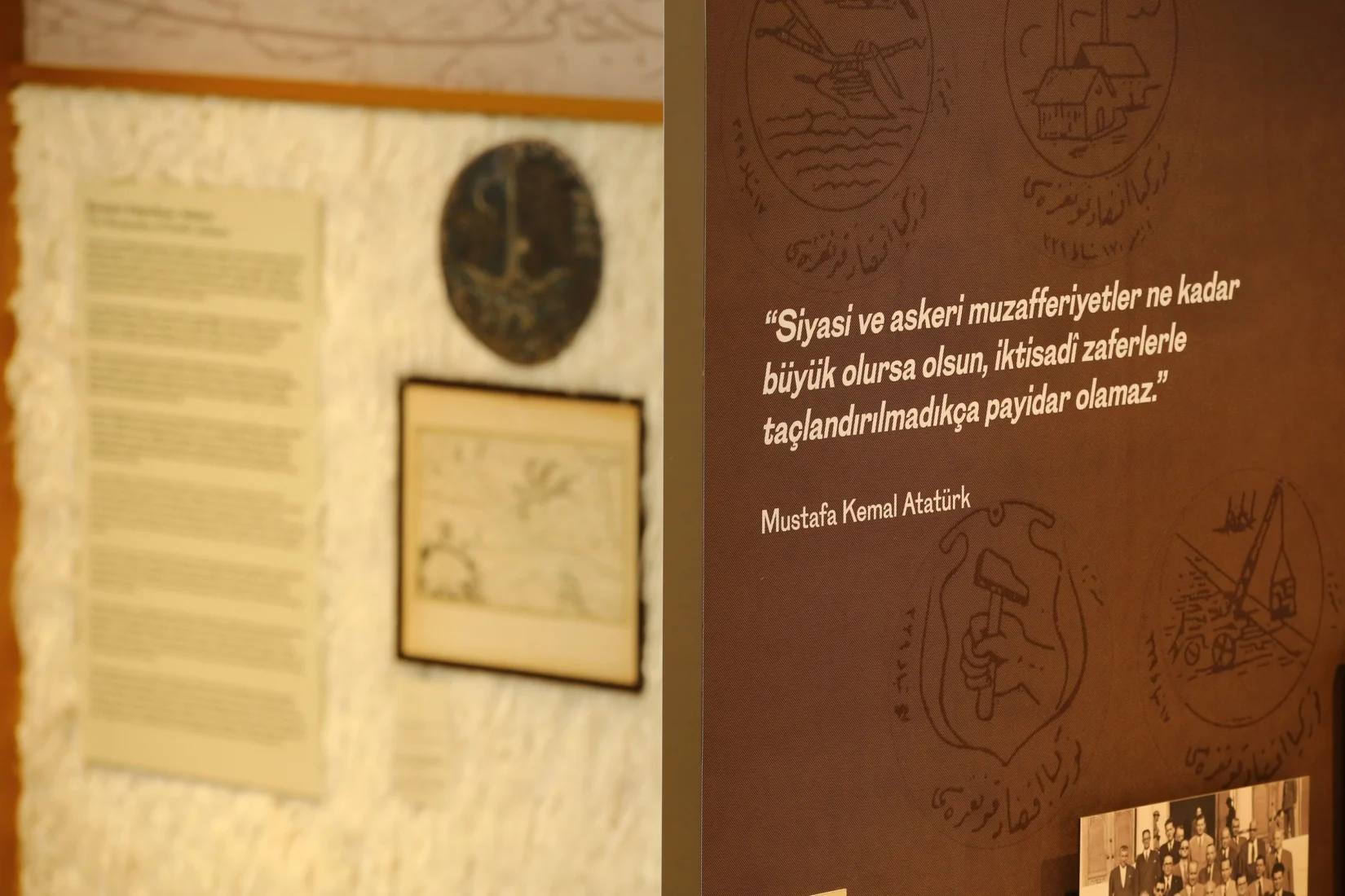 Koç sergisi kapsamında özenle hazırlanmış modern ve aydınlatmalı bir panoda, Türkiye Cumhuriyeti'nin kurucusu Mustafa Kemal Atatürk'e ait derin anlamlar taşıyan bir vecizenin ziyaretçilerin odak noktası olarak sergilendiği, düşündürücü bir anı yansıtan detaylı görsel.