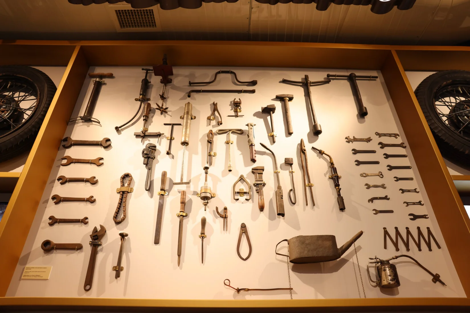 Bir masanın üzerinde sergilenen, aralarında küçük metal objeler, dekoratif bir kutu, cüzdan benzeri bir nesne ve heykelsi figürlerin bulunduğu çeşitli Koç sergisi eşyaları, zengin bir koleksiyonun parçası olarak detaylıca görünmektedir.
