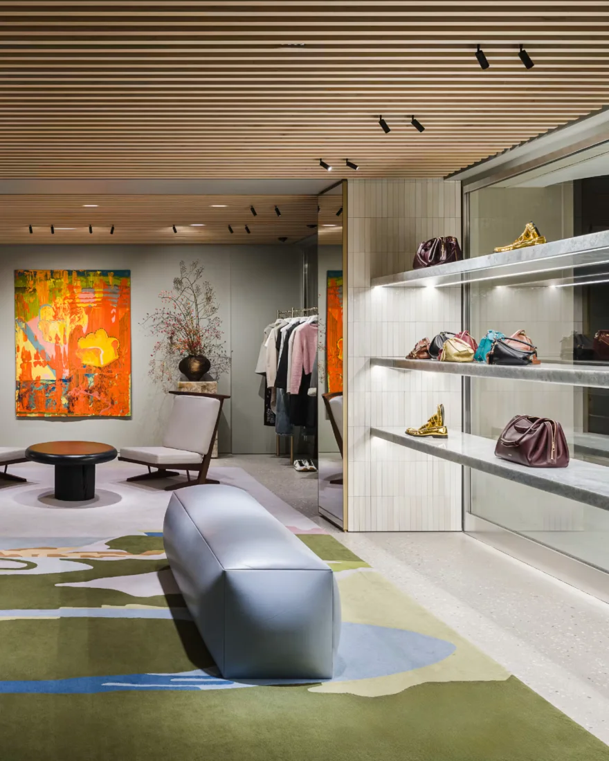 Modern ahşap çıtalı tavanı, zemindeki soyut desenli halısı ve duvardaki renkli sanat eseriyle dikkat çeken lüks bir butikte, aydınlatmalı raflarda sergilenen çeşitli renklerdeki zarif deri çantalar ve parlak altın renkli ayakkabılar, LVMH'nin eşsiz zanaat mükemmelliğini ve lüksün sırrını gözler önüne seriyor.