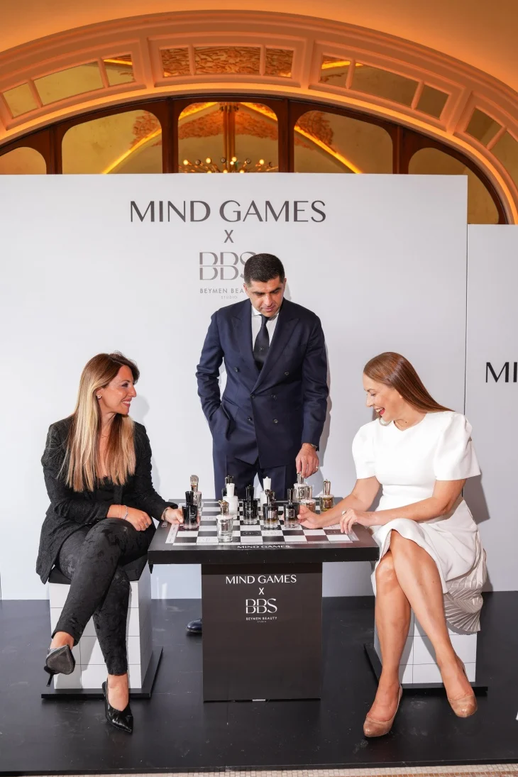 Mind Games Parfüm kurucusu Alex Shalbaf, profesyonel ve özenli bir duruşla, koyu renk takım elbisesi içinde, markasının vizyonunu ve koku dünyasındaki eşsiz yerini anlattığı bu röportajda, kameraya odaklanmış bir şekilde oturuyor.