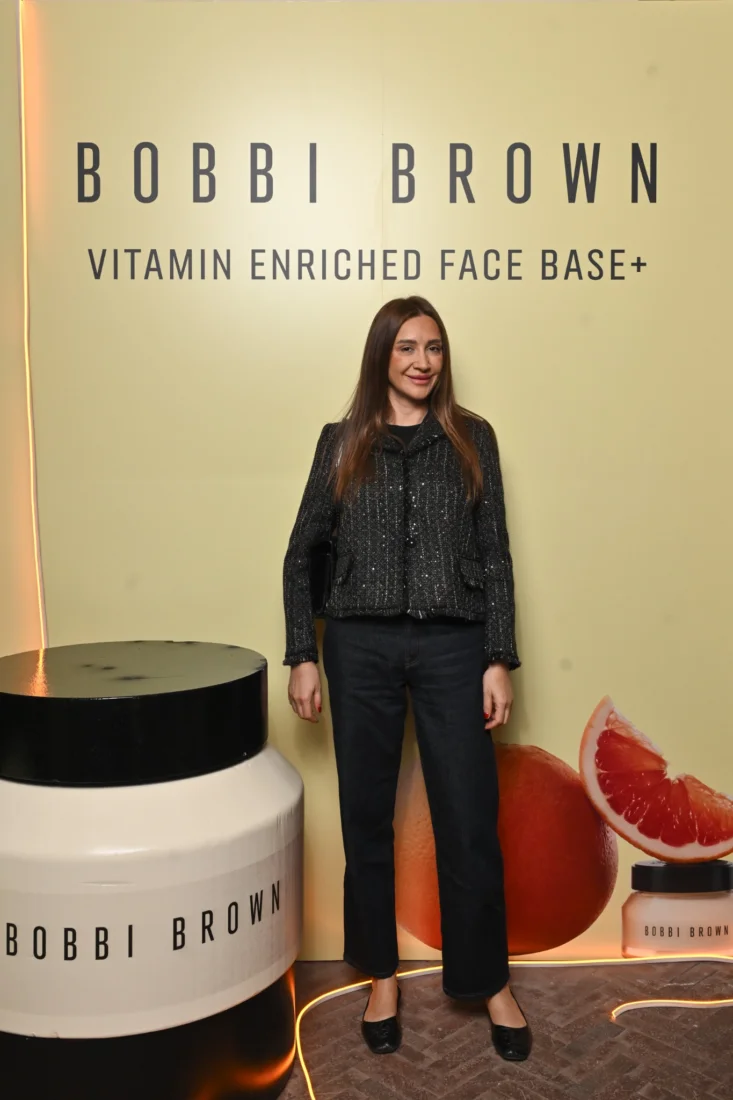 Modelin kusursuz görünen cildinde Bobbi Brown'ın imza doğal güzellik anlayışını ön plana çıkaran, zarif bir makyajla belirginleştirilmiş elmacık kemikleri ve dolgun dudakları, yumuşak bir ışık altında aydınlık ve canlı bir ifadeyle belirginleşiyor, bu da zahmetsiz ve modern bir şıklığı gözler önüne seriyor.