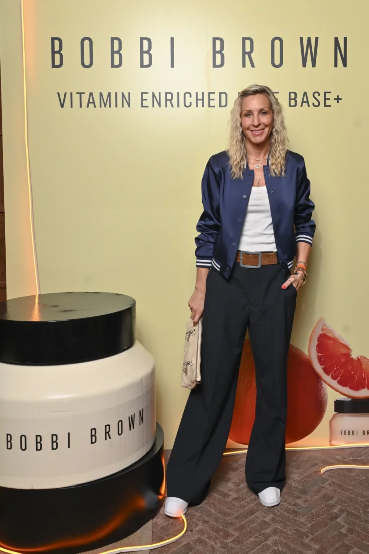 Bir kadın, Bobbi Brown'ın doğal güzelliği ön plana çıkaran makyajıyla pürüzsüz ve ışıltılı cildini sergiliyor, yüzündeki hafif tebessüm ve gözlerindeki sıcak ifadeyle markanın modern ve kendinden emin kadın imajını yansıtıyor.