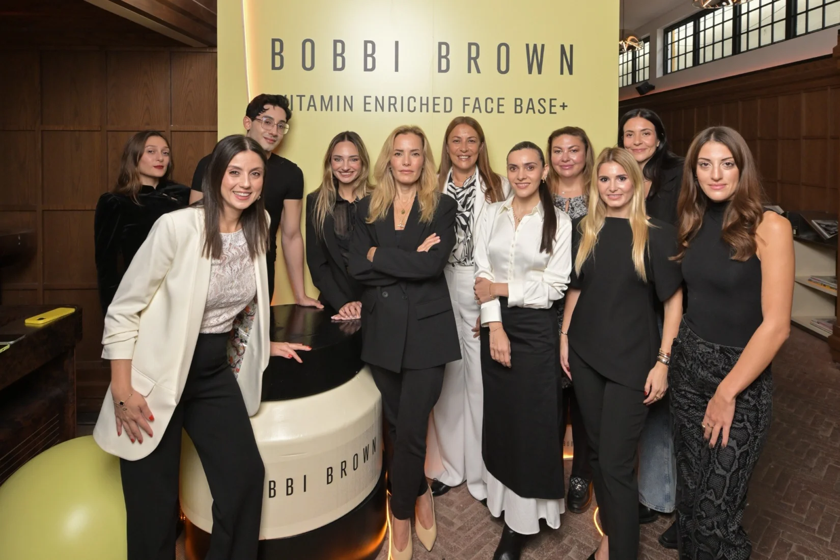 Bobbi Brown makyajının zarif dokunuşunu yansıtan, ışıkla aydınlanmış, doğal güzelliği ön plana çıkaran bir kadının yakın çekim portresi; pürüzsüz cildi, hafif renkli dudakları ve belirgin kirpikleriyle modern ve taze bir görünüm sunarak, markanın felsefesini vurguluyor.