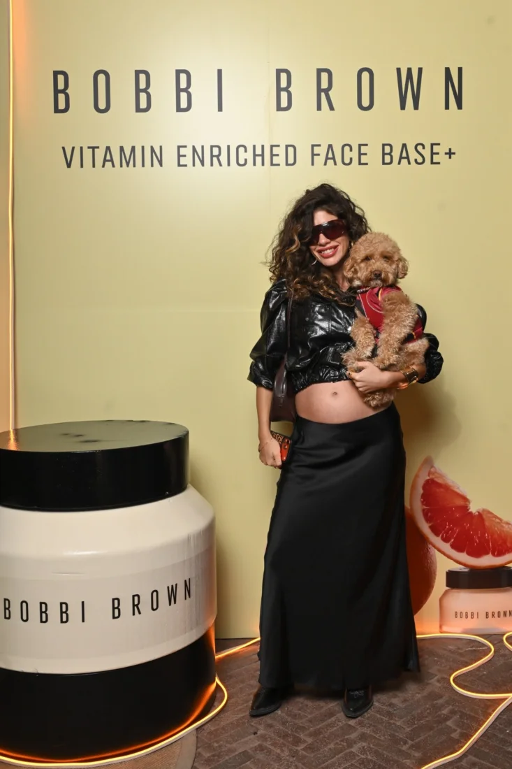 Kadınların çoğunlukta olduğu, şık giyimli bir grup konuk, canlı ve modern bir iç mekan ortamında, gülümseyerek keyifli sohbetler ederken, muhtemelen bir Bobbi Brown etkinliğinde bir araya gelmiş.