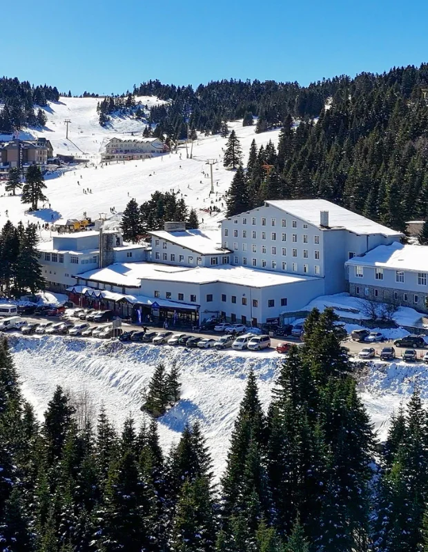 Otel Fahri'nin sıcak ve davetkar atmosferini yansıtan modern bir oda görüntüsü; bembeyaz çarşaflarla özenle hazırlanmış geniş yatak, şık bir başlık, odanın bir köşesinde yer alan konforlu koltuk ve dışarıdaki manzarayı içeri taşıyan aydınlık penceresiyle konuklarına huzurlu bir konaklama deneyimi vadediyor.
