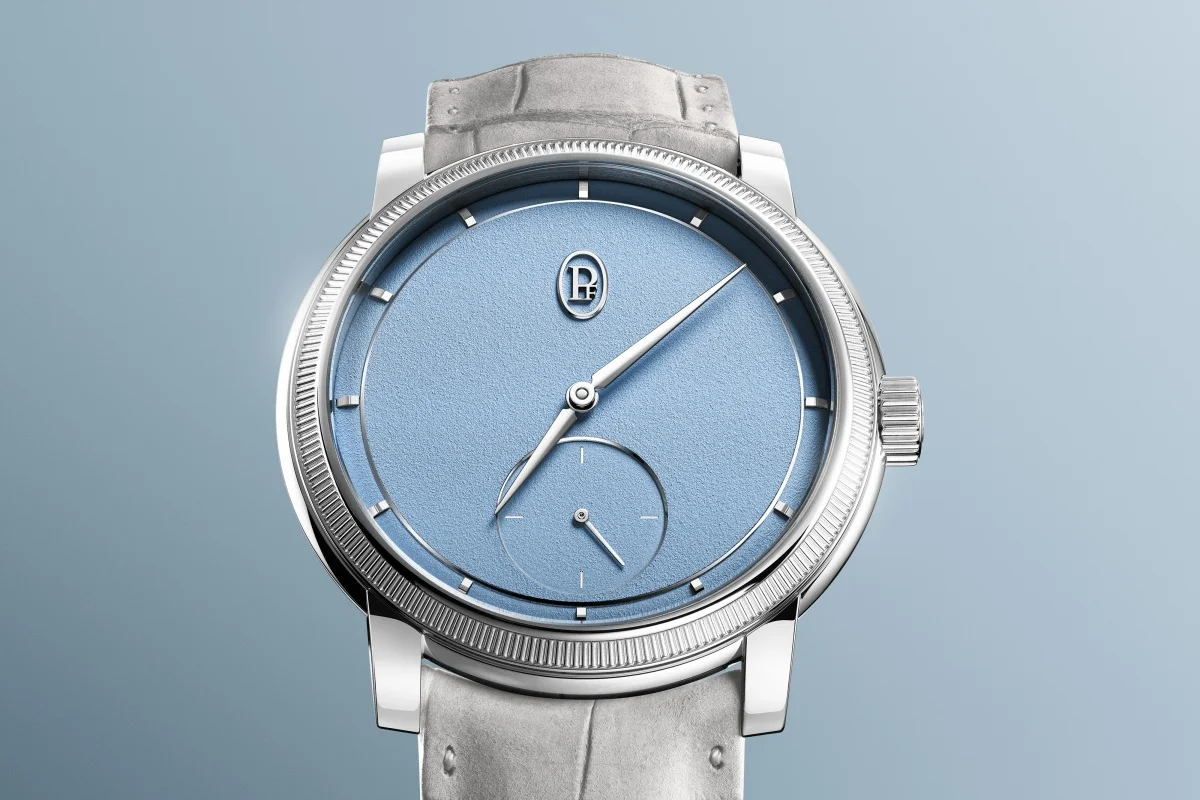 Parmigiani Fleurier Toric Petite Seconde Platinum Morning Blue kol saatinin yakın çekiminde, yivli bezelli parlak platin kasasıyla dikkat çeken, sabah mavisinin zarif dokulu kadranında gümüşi ibreler, altıda küçük saniye alt kadranı ve uyumlu mavi deri kayışı, lüks işçiliği gözler önüne seriyor.