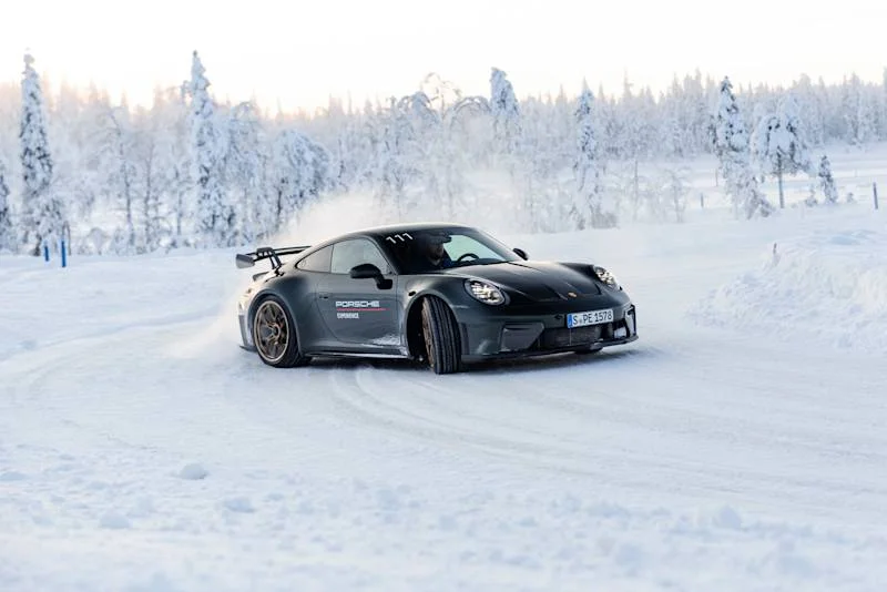 Beyaz bir Porsche, karla kaplı ve buzlu bir Finlandiya pistinde ustalıkla drift yaparak ilerlerken, seyahati bir öğrenme deneyimine dönüştüren skillcation trendine uygun olarak buz sürüşü ve ileri araç kontrolü becerilerinin geliştirildiği heyecan verici bir anı yansıtıyor.