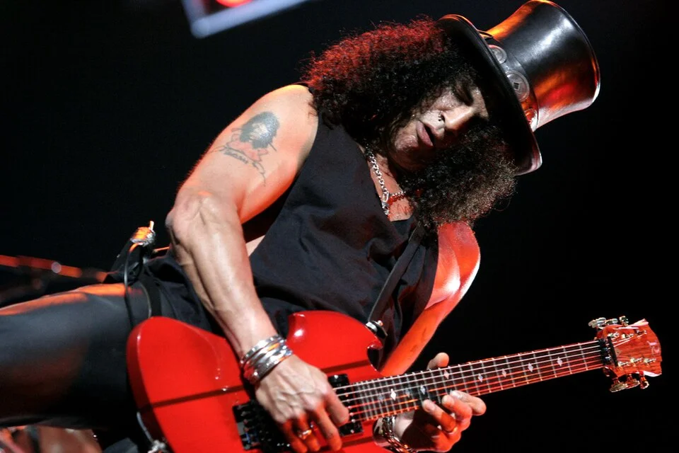 Rock efsanesi Slash, ikonik şapkası ve gitarıyla İstanbul'daki büyük bir konserde sahne ışıkları altında, enerjik ve büyüleyici bir canlı performans sergilerken, seyircilere unutulmaz anlar yaşatıyor.