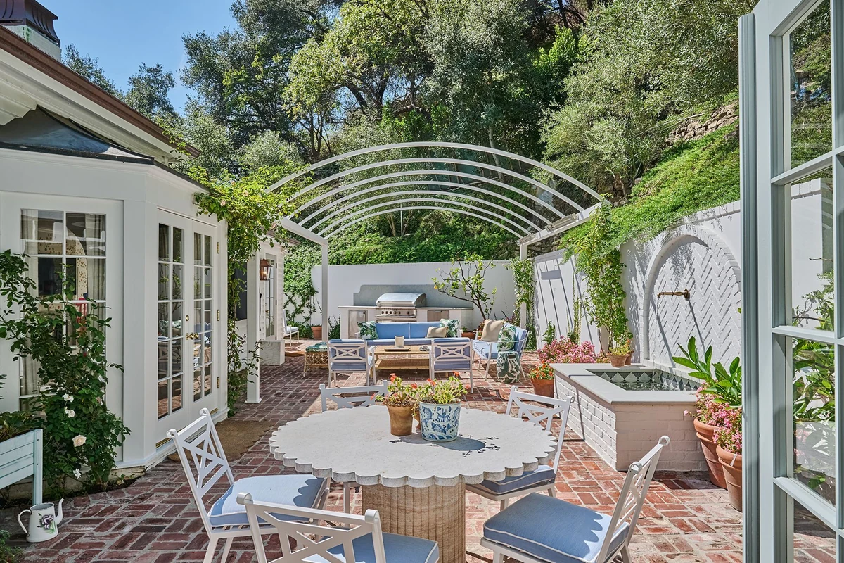Taylor Swift’in eski Beverly Hills evinin tuğla döşeli bahçe terasında oturma grubu, yemek masası, çeşme ve barbekü